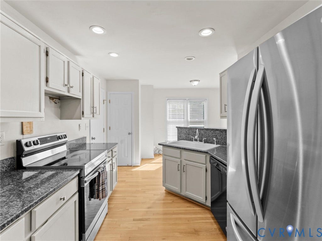 Kitchen with light wood-finish flooring, recessed lighting, stainless steel appliances, white cabinetry, and a double basin sink
