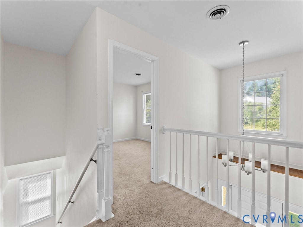 Carpeted hallway with white walls and trim