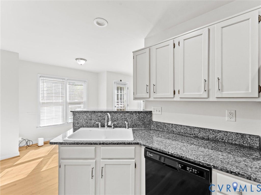White shaker-style cabinetry with dark hardware, a white drop-in sink, and speckled stone countertops