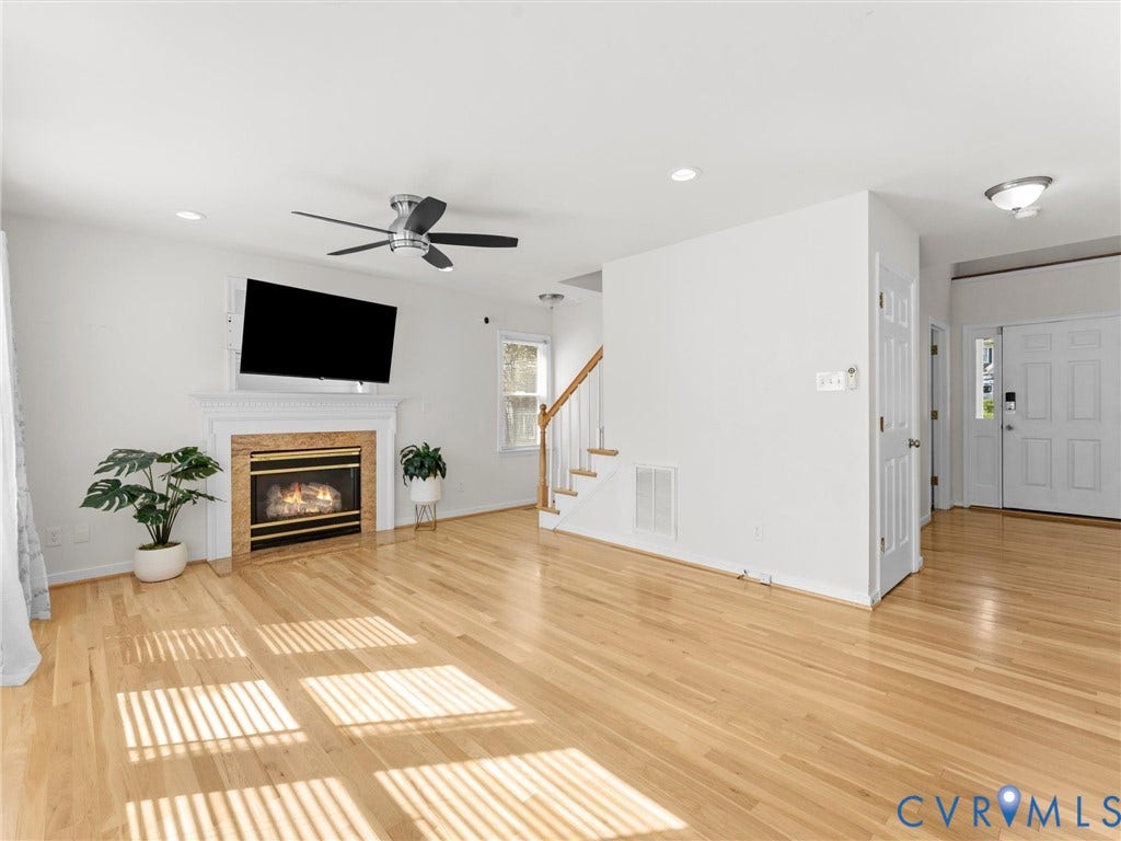 Spacious living area featuring wood-finish flooring, a fireplace with a mantel, a ceiling fan, and recessed lighting