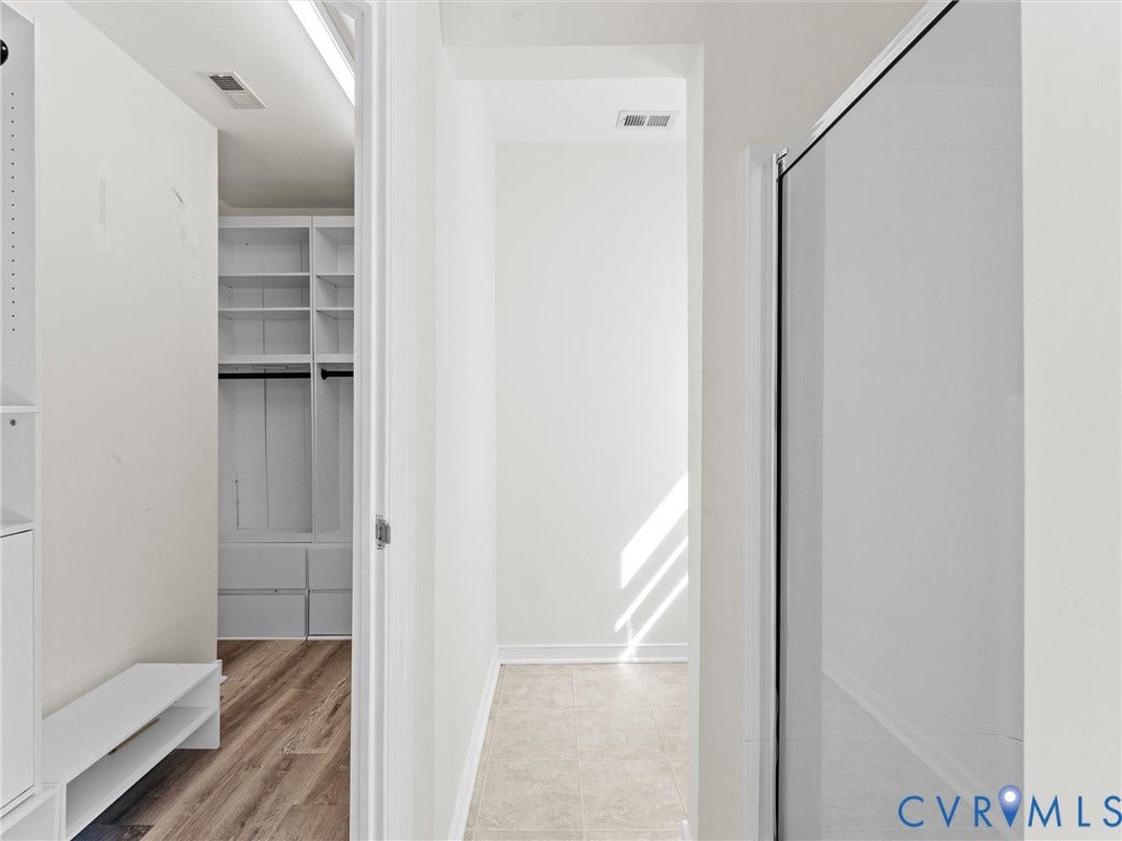 Built-in closet shelving system with drawers and hanging rods, wood-finish flooring, and white walls