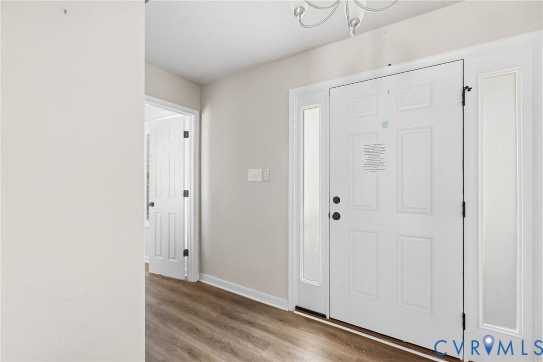 Front entry with side-light panels, wood-finish flooring, and a six-panel door