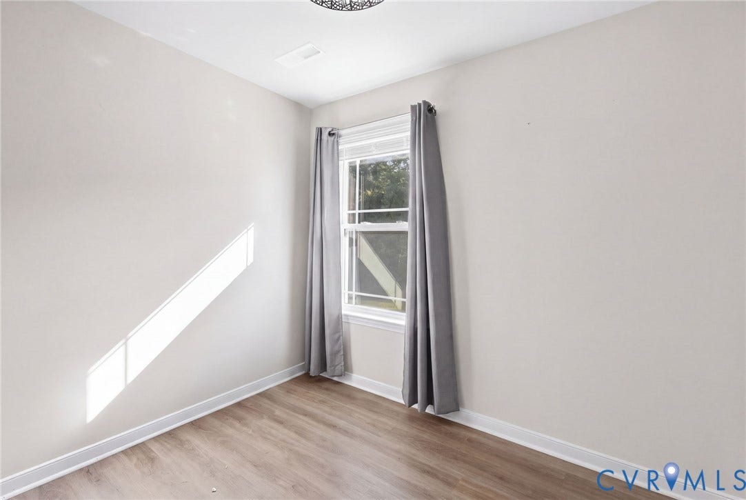 Wood-finish flooring, white walls, and a single window with white trim