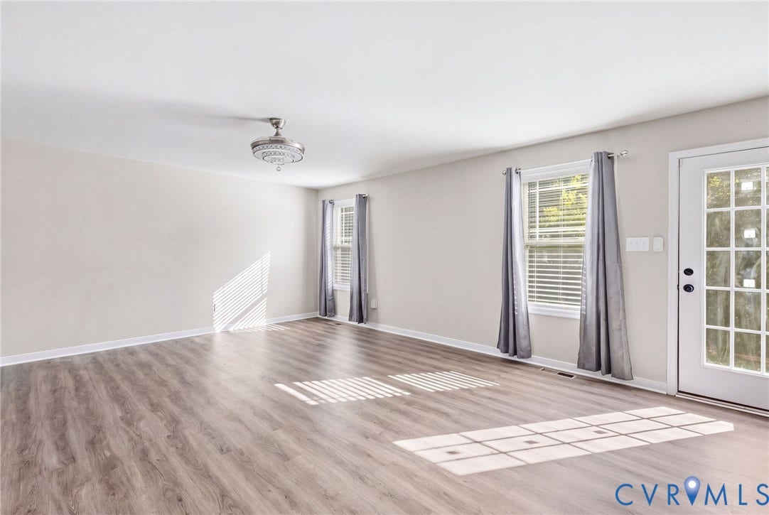 Spacious room with wood-finish flooring, white walls, and a ceiling-mounted light fixture