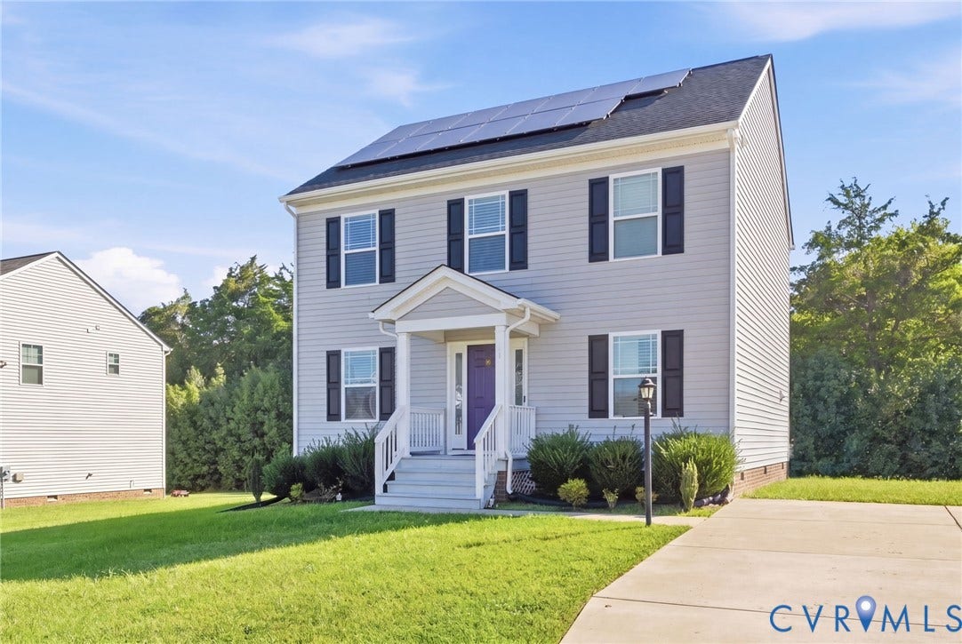 Two-story property featuring light gray siding, a dark roof, and solar panels