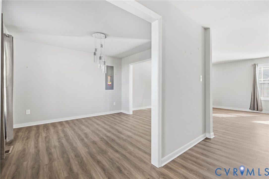 Wood-finish flooring throughout, white trim, and a contemporary multi-light pendant fixture
