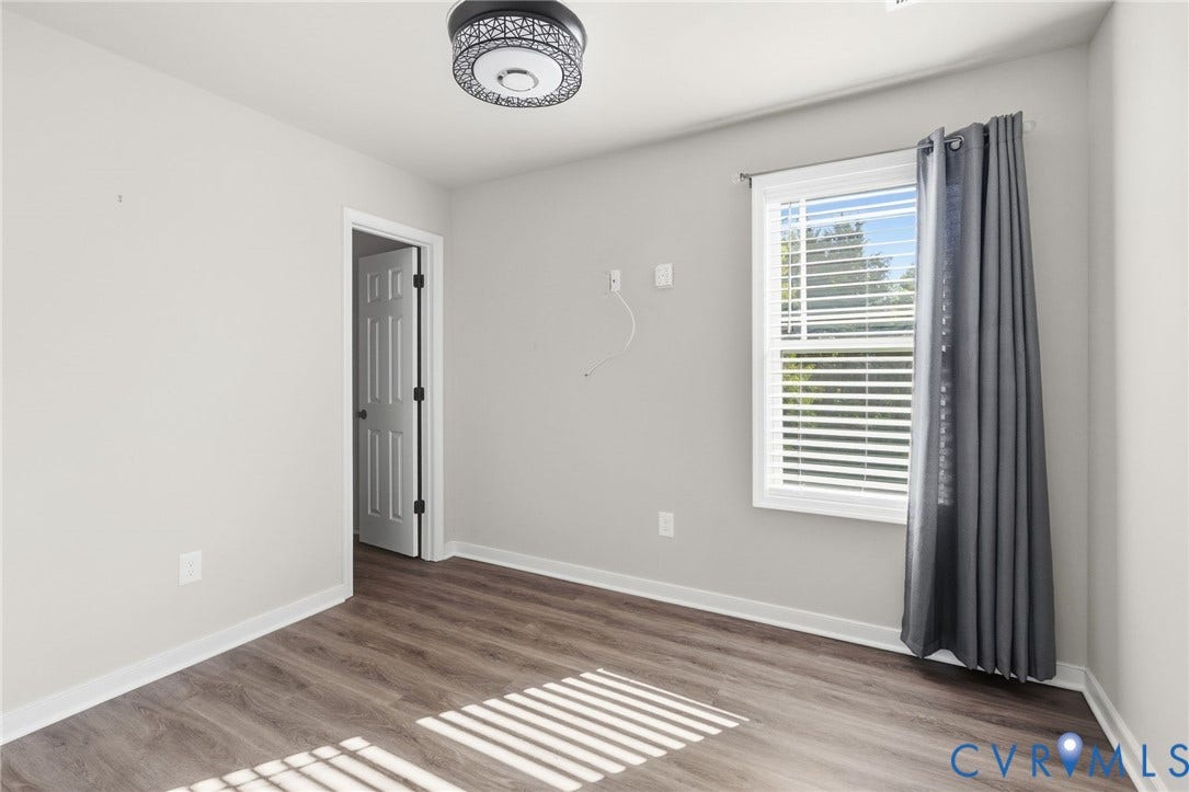 Wood-finish flooring, flush mount ceiling light, white trim, and a window with blinds