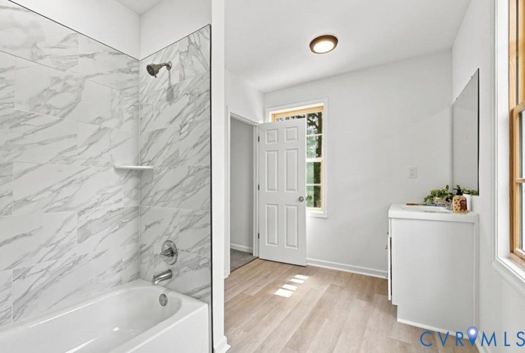 104 E Fillmore Street, Petersburg, VA 23803 Tub and shower combination with large format tile surround, light wood-finish flooring, and a single vanity