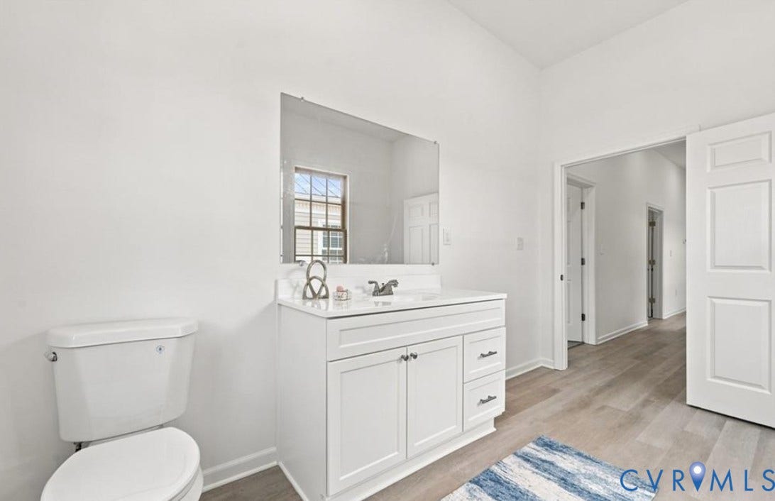 104 E Fillmore Street, Petersburg, VA 23803 White vanity with a rectangular sink, wall-mounted mirror, and wood-finish flooring