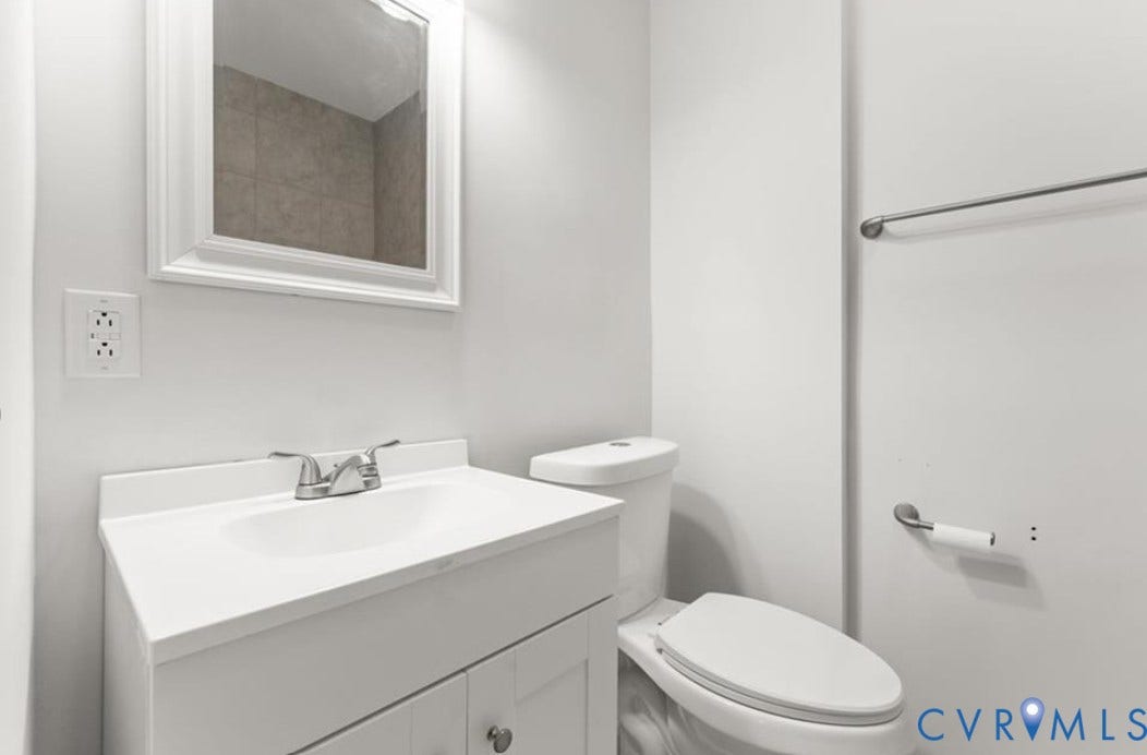 222 Elm Street, Petersburg, VA 23803 White vanity with integrated sink, chrome faucet, framed mirror, and toilet