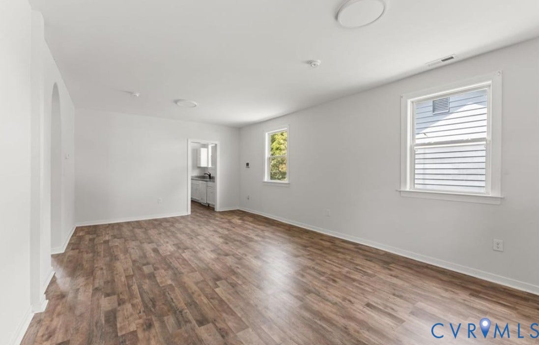 222 Elm Street, Petersburg, VA 23803 Spacious interior featuring wood-finish flooring, white walls, two windows, and a doorway leading to an additional space