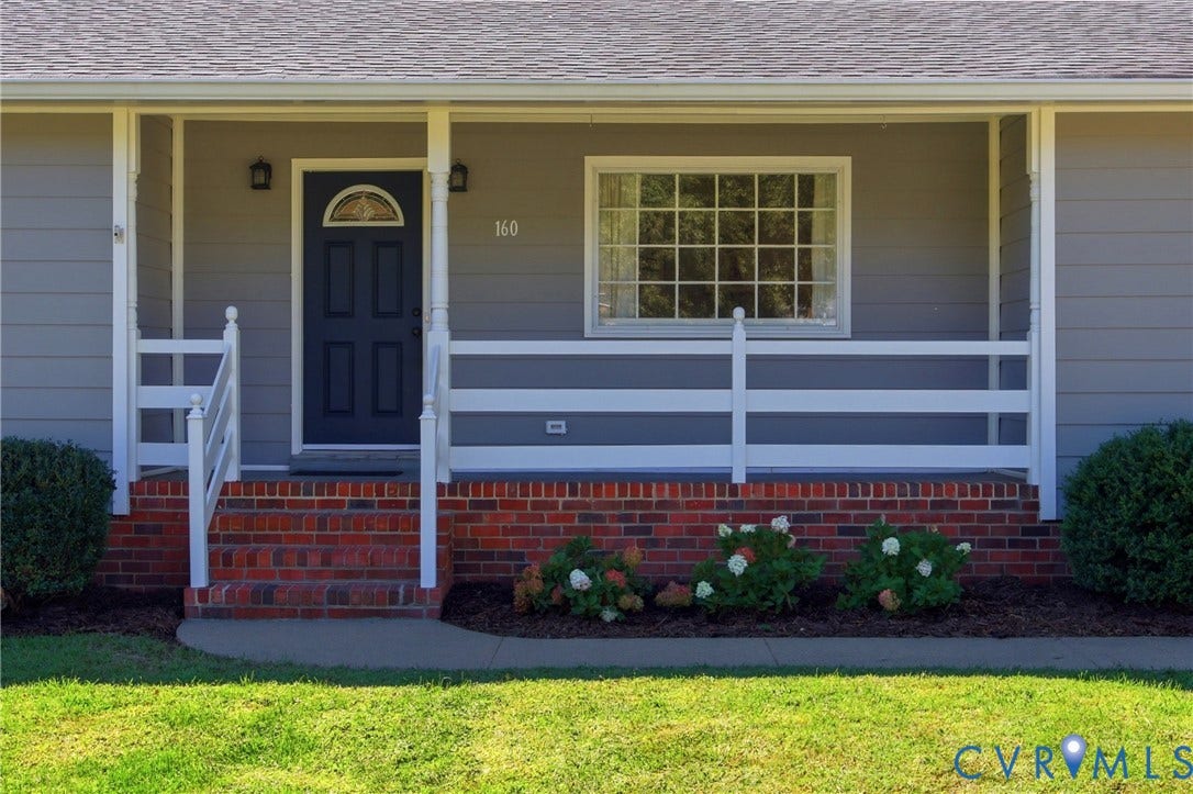 Covered front porch with white railings and gray siding