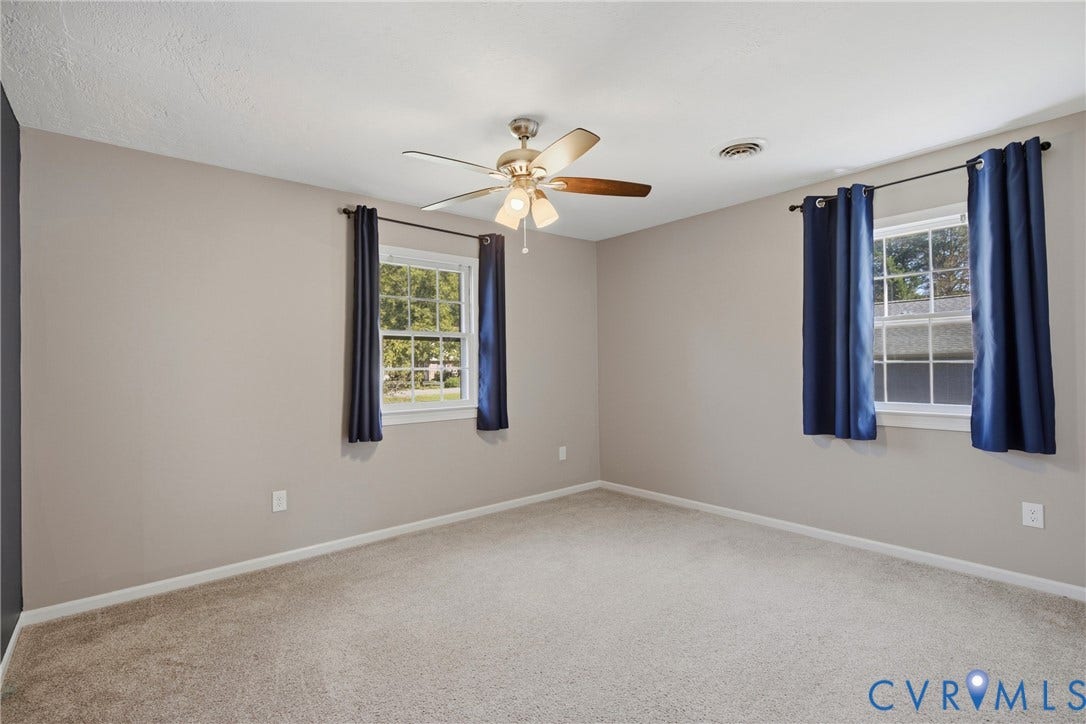 Plush carpeting, two windows with sills, and a ceiling fan with integrated lighting