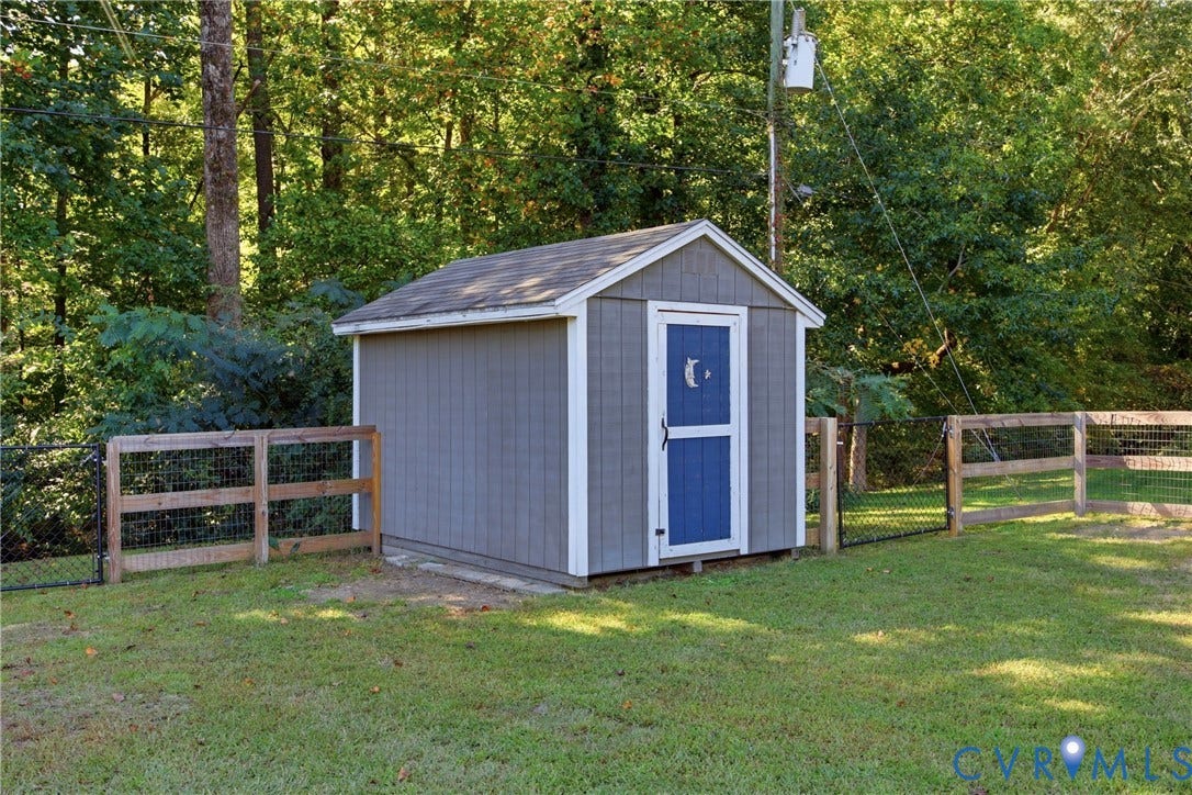 Grey-sided storage shed with a blue screen door, featuring a shingle roof and white trim