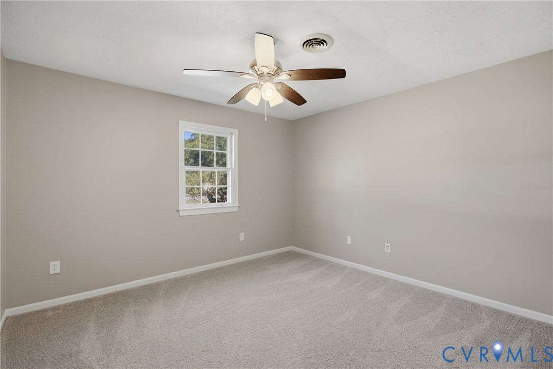 Neutral-toned walls, light-colored carpeting, a multi-pane window, and a ceiling fan with integrated lighting