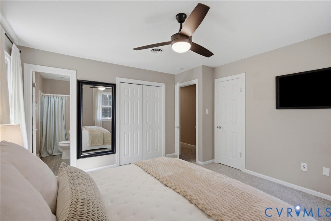 Carpeted bedroom with a ceiling fan, light gray wall color, and white bi-fold closet doors