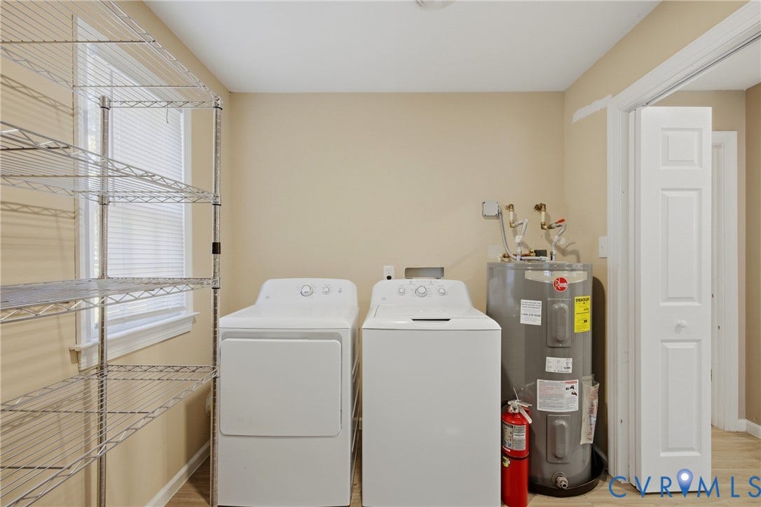 Utility room featuring a window with blinds, bi-fold door, and light-toned walls