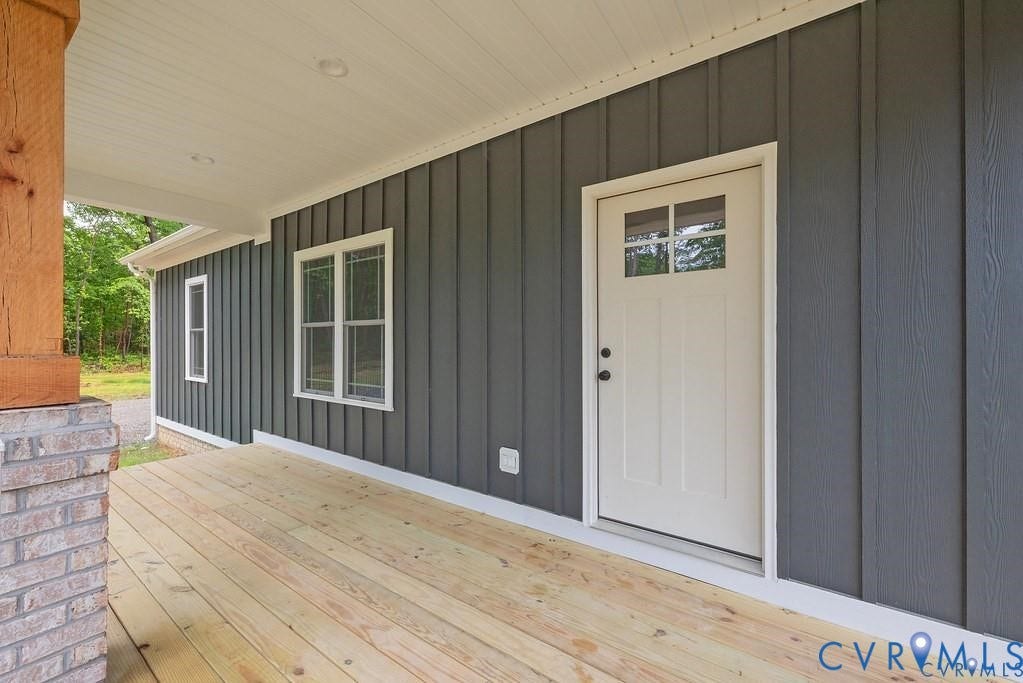 5301 Chimney Springs Drive, Goochland, VA 23063 Covered porch with wood flooring, board and batten siding, recessed lighting, and a paneled entry door with windowpanes