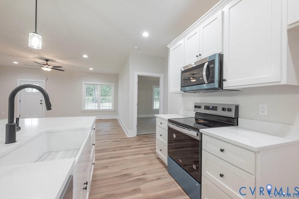 5301 Chimney Springs Drive, Goochland, VA 23063 Kitchen featuring white shaker-style cabinetry, stainless steel appliances, a deep basin sink with a black gooseneck faucet, and light-toned wood-finish flooring