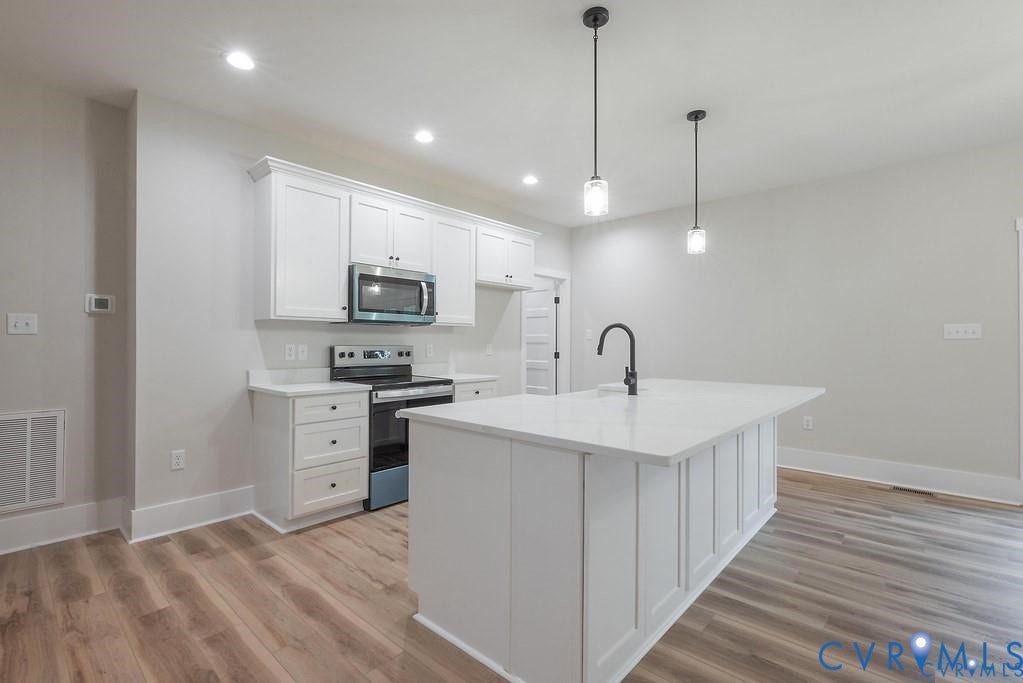 5301 Chimney Springs Drive, Goochland, VA 23063 Kitchen featuring white shaker cabinetry, stainless steel appliances, a center island with countertop, a black gooseneck faucet, and wood-finish flooring