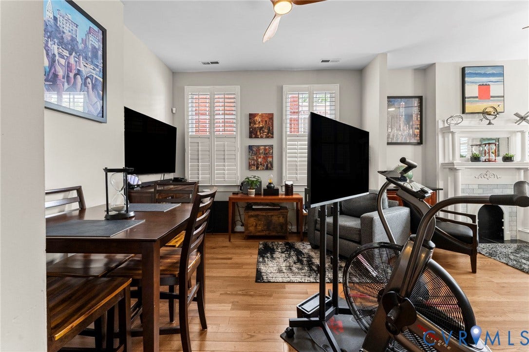 Hardwood flooring, white window shutters, ceiling fan, decorative fireplace surround, and recessed lighting