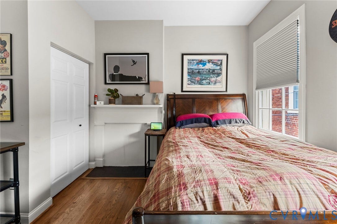 Wood-finish flooring, white bi-fold closet doors, decorative fireplace mantel, white window trim, and cellular window shades