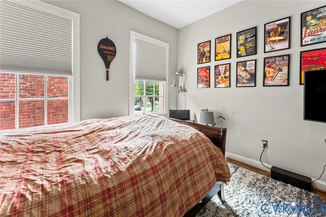 Two double-hung windows with white blinds, wood-finish flooring, and white baseboards