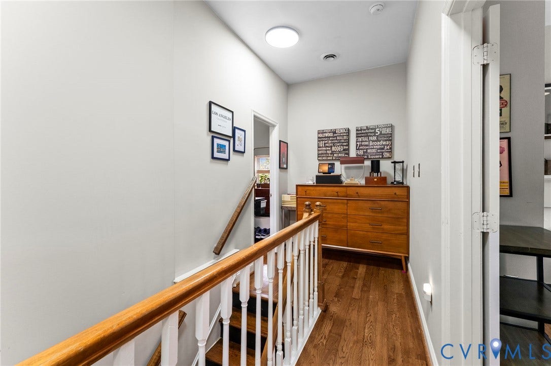 Wood-finish flooring with a white spindle railing and wood-finish handrail
