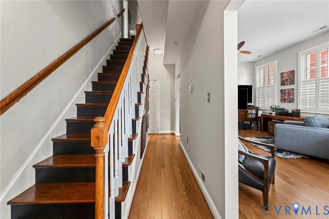Hardwood flooring, painted white walls, wood-finish staircase with white risers, ceiling-mounted light fixture, white window shutters