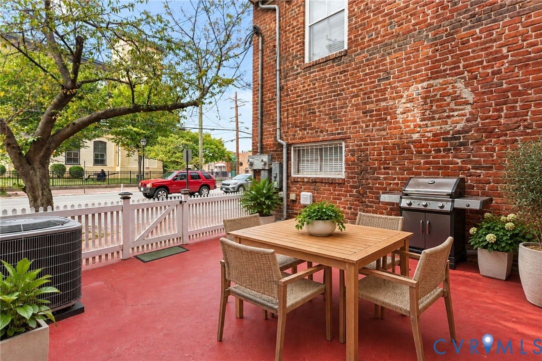 Patio with a red concrete surface, white picket fence, and a brick exterior wall