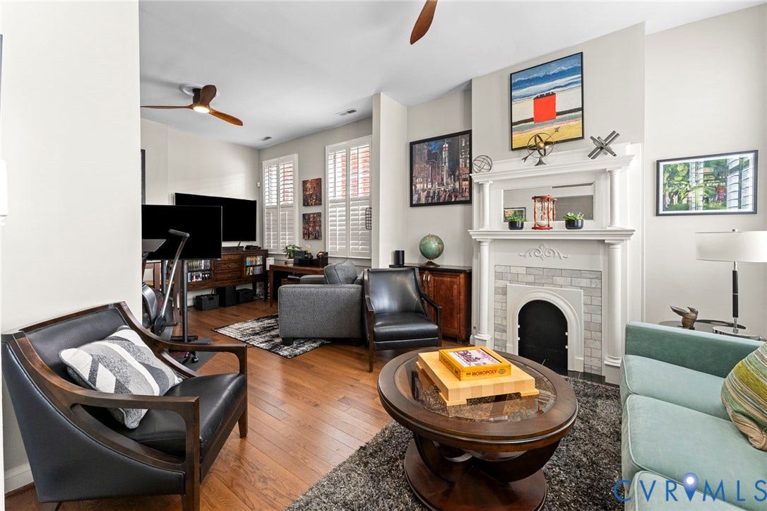 Hardwood flooring, white plantation shutters, decorative fireplace with tile surround, white mantel, and ceiling fans