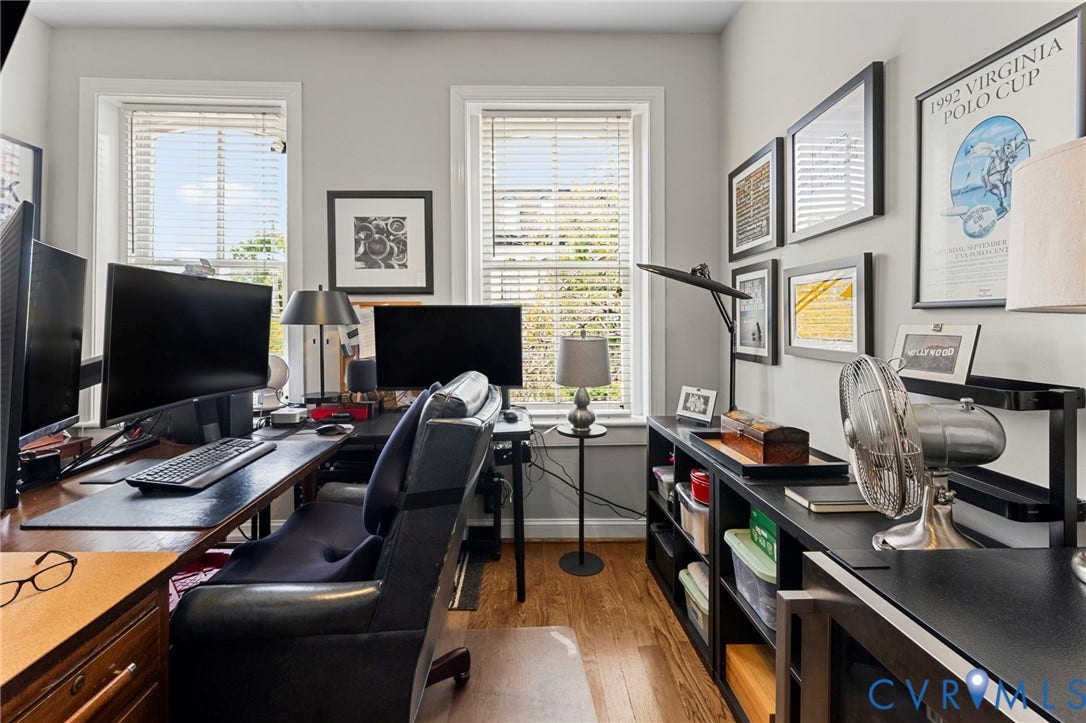 Wood-finish flooring, multiple windows with blinds, light gray wall paint, and built-in shelving