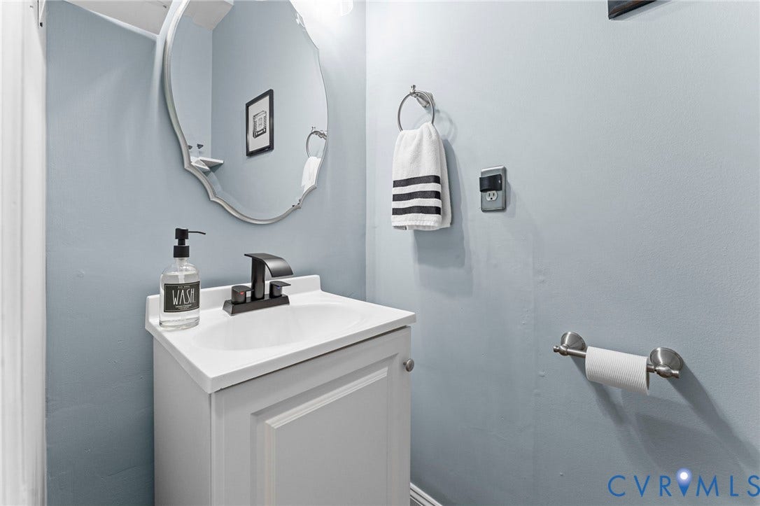 White vanity with integrated sink, matte black faucet, and oval wall mirror