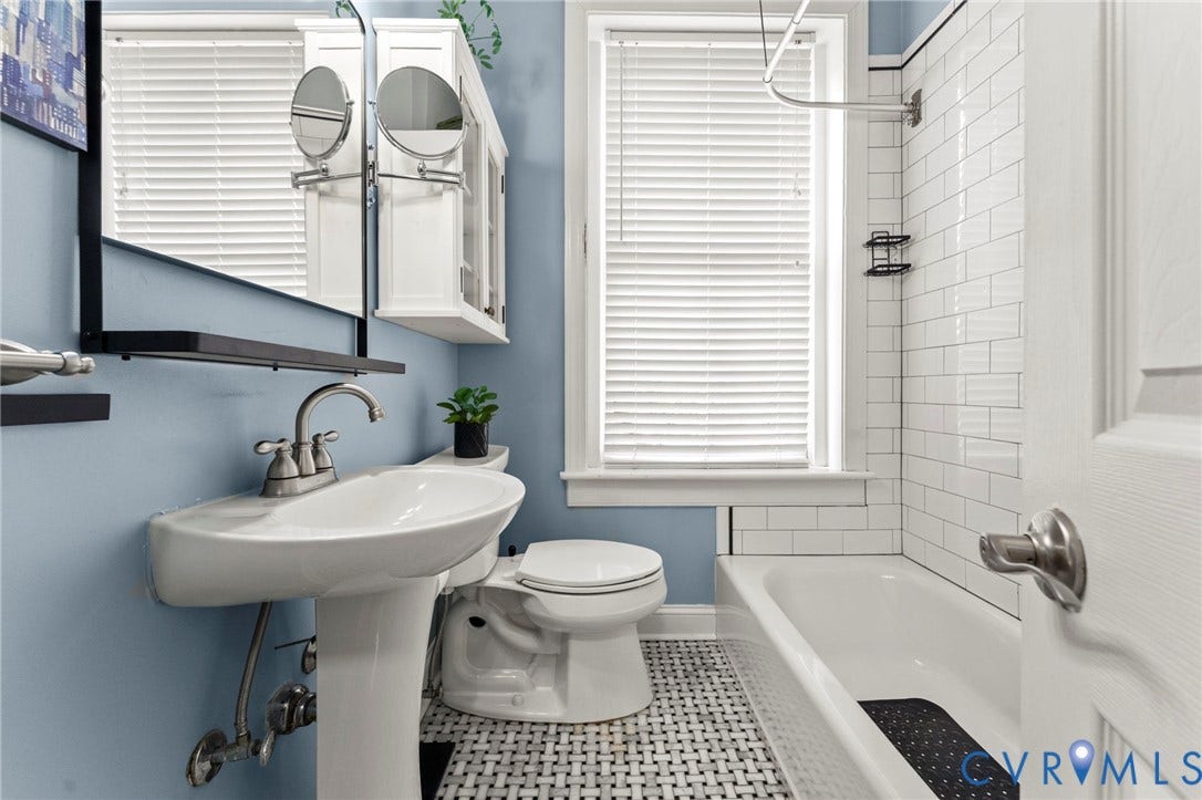 Pedestal sink with a two-handle faucet, white subway tile shower surround, and basketweave tile flooring