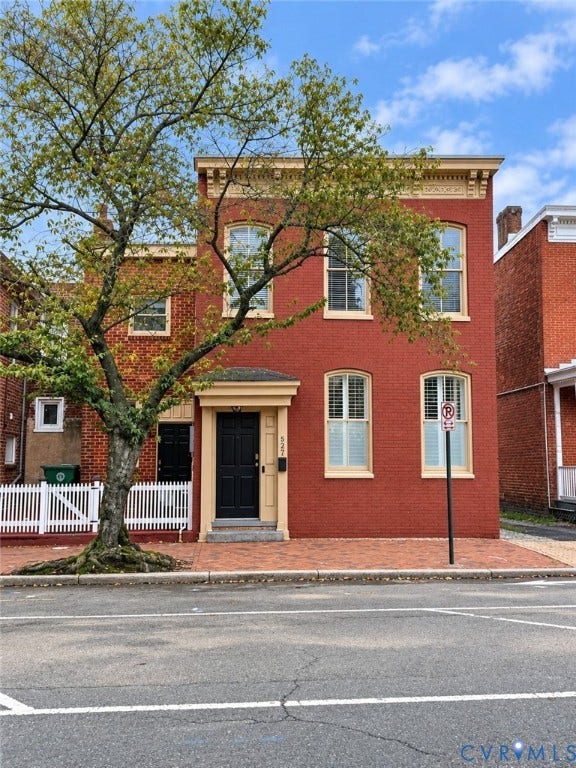 Red brick exterior with white trim windows and a black entry door