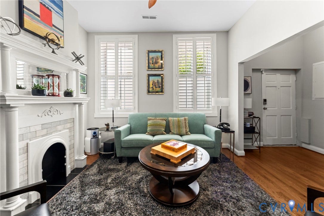 Decorative fireplace with white tile surround, white plantation shutters, and wood-finish flooring