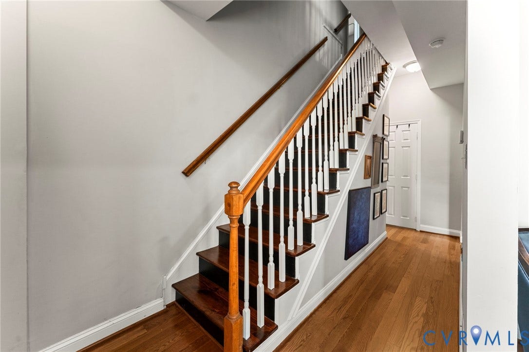 Hardwood flooring, wood-finish staircase with white balusters, and a solid wood handrail
