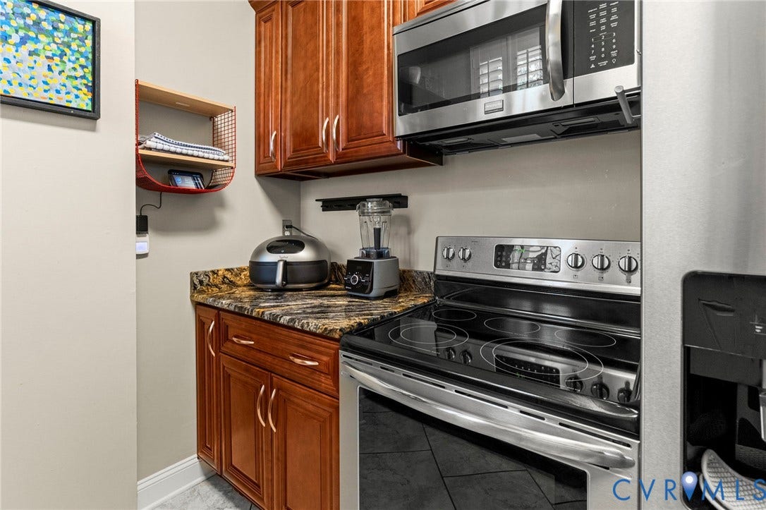 Kitchen featuring wood cabinetry, stone-finish countertops, stainless steel appliances, and a built-in microwave