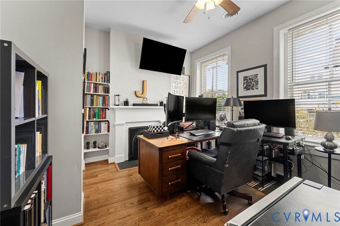 Hardwood flooring, painted walls, ceiling fan, white window trim, and a fireplace with a white mantel