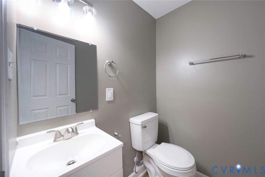 634 Fayette Avenue, Richmond, VA 23222 Vanity with an integrated sink, brushed nickel faucet, mirror, wall-mounted light fixture, and a toilet