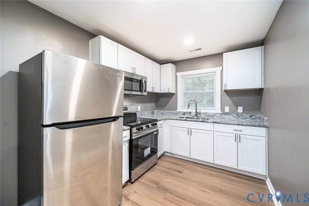 634 Fayette Avenue, Richmond, VA 23222 Kitchen with wood-finish flooring, white cabinetry, stainless steel appliances, and a window above the sink