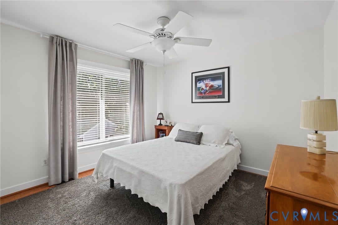 White walls, window with blinds and drapes, ceiling fan with light, and wood-look laminate flooring