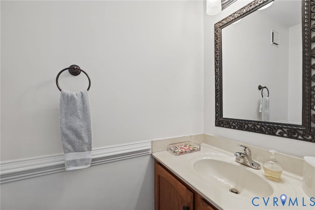 1/2 bath off lower hall, Vanity with integrated sink, chrome faucet, and ornate framed mirror