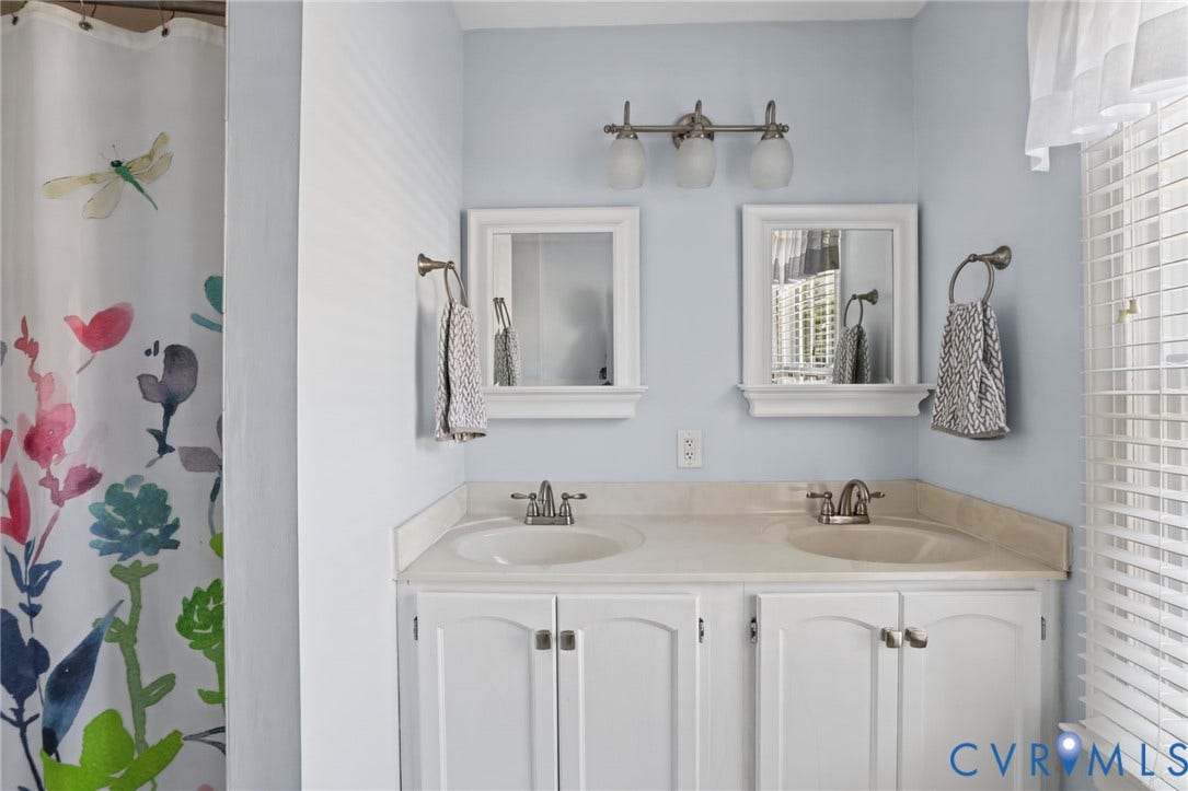 Dual vanity with integrated sinks, white cabinetry, and brushed nickel hardware