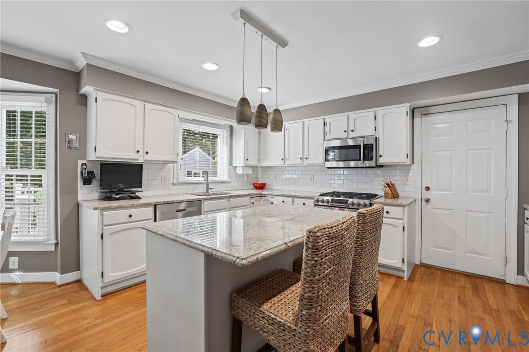 White cabinetry with brushed nickel hardware, light-toned stone countertops and subway tile backsplash