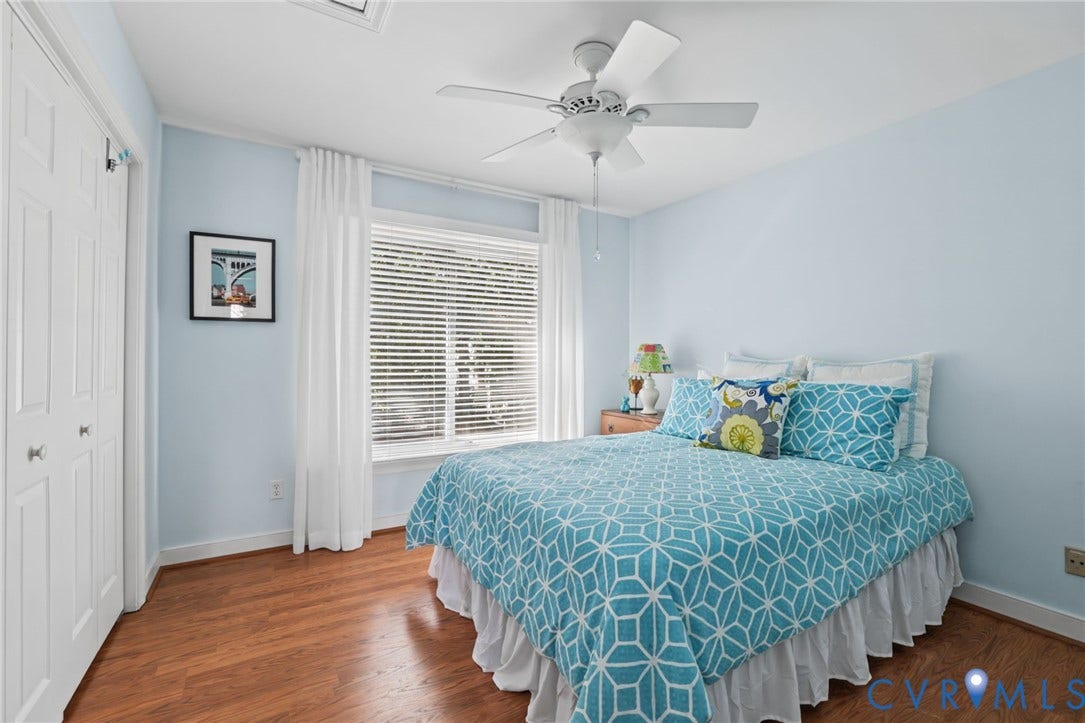Wood-look laminate flooring, white bi-fold closet doors, large window with white blinds, and a ceiling fan with integrated lighting
