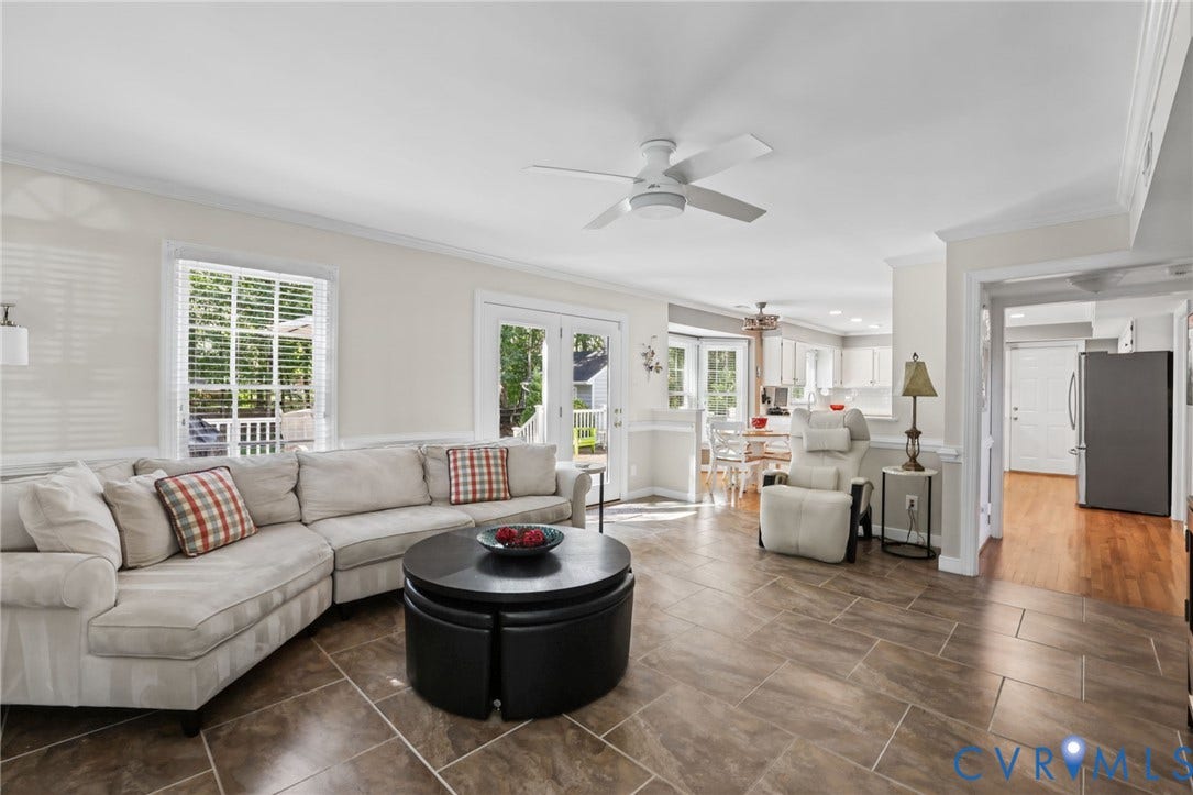 Spacious living area featuring large format tile flooring, crown molding, a ceiling fan, and abundant natural light from multiple windows and French doors