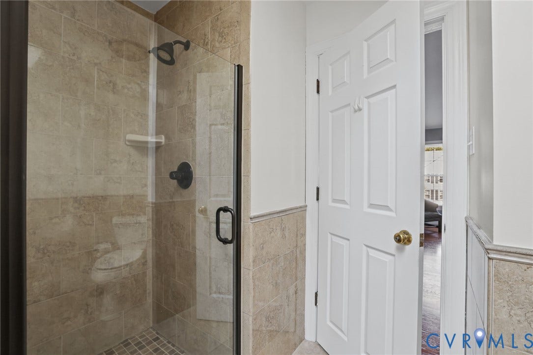 Glass-enclosed shower with subway tile surround, dark bronze fixtures, and a mosaic tile floor