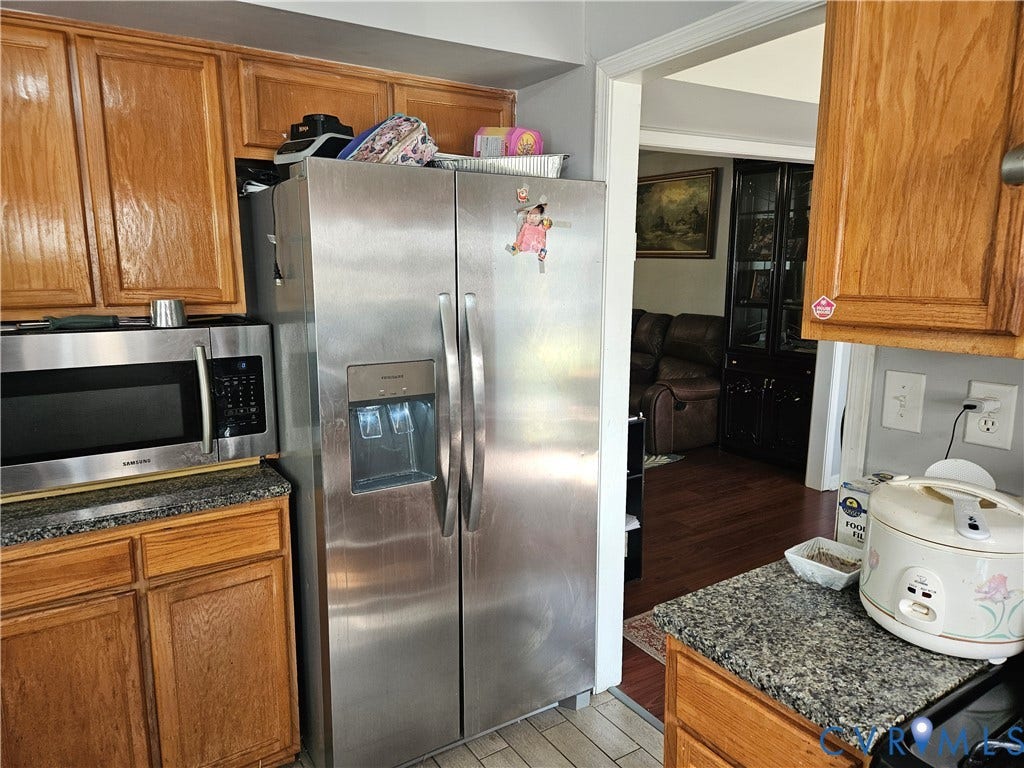 1307 Spruance Road, Outten Woods, Richmond, VA 23225 Wood cabinetry, granite-patterned countertops, stainless steel microwave, and stainless steel refrigerator with an external ice and water dispenser