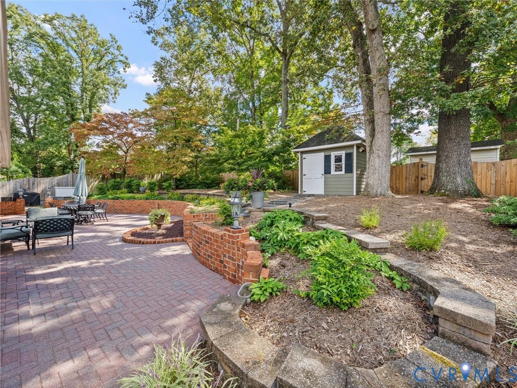 7723 Stuart Hall Road, Rollingwood Terrace, Henrico, VA 23229 Expansive brick paver patio with a curved brick retaining wall, terraced landscaping beds, and a detached storage shed